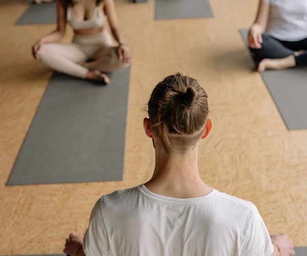 Diverse group of people sitting peacefully on yoga mats in a bright studio.