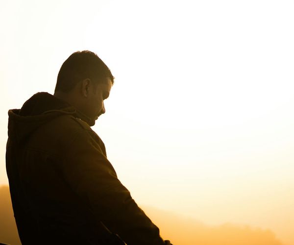Silhouette of a person meditating on a hill during a vibrant sunrise.